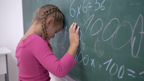 unglücklich-Schulmädchen-in-der-Nähe-von-Board-mit-Beispielen-zur-Mathematik-in-der-Grundschule-Klasse