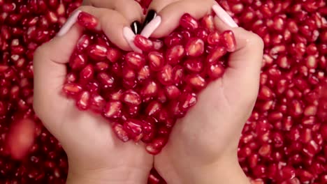 Falling-grains-of-pomegranate-into-the-hands-.-Slow-motion