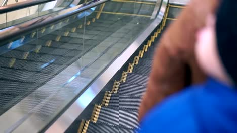 Mom-and-her-son-are-going-down-the-escalator.-They-are-in-winter-clothes,-came-to-the-mall