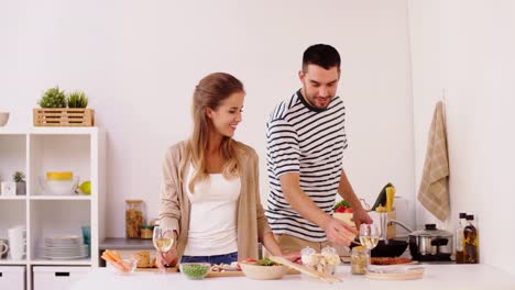 couple-cooking-food-and-drinking-wine-at-home