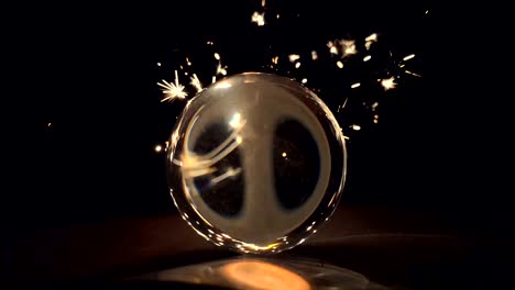 Burning-sparkler-behind-a-glass-ball-on-a-black-background.