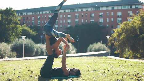 Schönes-paar-praktizieren-Acro-Yoga-am-Morgen