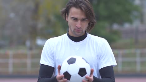 Retrato-de-un-chico-en-un-deportivo-con-un-fútbol-de-camiseta-bola-en-sus-manos-y-estrictamente-mirando-el-tipo-de-deportes-de-la-cámara-con-una-pelota-en-sus-manos-con-una-mirada-descarada