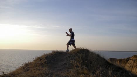 young-pugilist-male-practicing-boxing-blows-before-sparring-on-hill-near-river