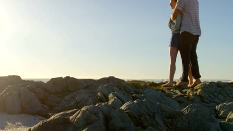 Romantic-young-couple-embracing-on-rock-at-beach-4k