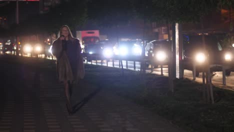 A-girl-in-a-short-skirt-goes-along-the-night-road-and-drinks-wine-from-the-bottle-4K-Slow-Mo