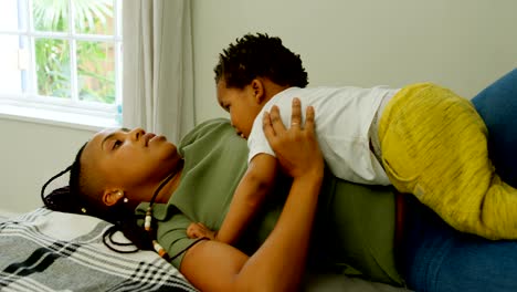 Side-view-of-young-black-mother-playing-with-her-son-on-bed-in-a-comfortable-home-4k