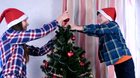 Mutter-und-Sohn-in-Weihnachtsmützen-setzen-den-Turm-auf-den-Weihnachtsbaum.