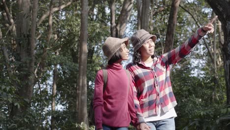 Mittlerer-Weitschuss.-Asiatische-Familien-mit-Mutter-und-Tochter-halten-Hand-beim-Spaziergang-in-der-Morgen-Natur-in-Wald-Farbe-grün.-Das-Konzept-des-Familienlebens-im-Urlaub