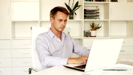 man-sitting-at-working-desk-with-laptop