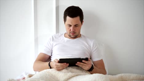 Man-using-tablet-PC-when-lying-in-bed