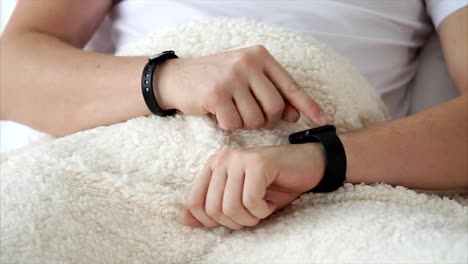 Man-using-smart-watch-when-lying-in-bed-at-home