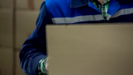 Factory-worker-vest-seals-up-boxes-with-security-tape.