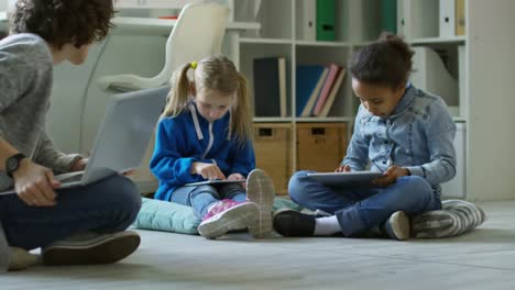 Female-Teacher-and-Kids-Using-Tablets-for-Drawing-at-Lesson