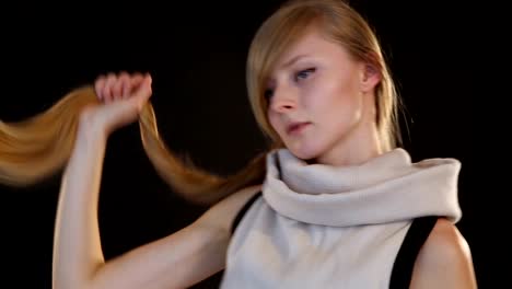 blonde-model-of-European-appearance-posing-in-front-of-camera-in-studio-on-black-background