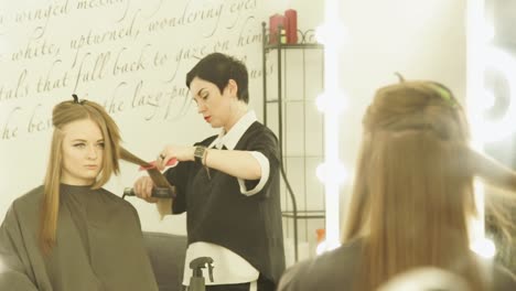 Friseur-Frisur-mit-Zange-Haar-und-Kamm-für-Haarglättung-im-Beauty-Salon-zu-machen.-Enge-Upfemale-Friseur-lange-Haare-glätten.-Frau-Haarstyling-im-Friseur-salon