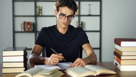 Konzentrierte-Studierender-zu-Hause.-Vorbereitung-auf-die-Universität,-lernen,-Bildung-und-Schulkonzept.-Mann-mit-Büchern-oder-Lehrbücher-schreiben-zu-notebooks