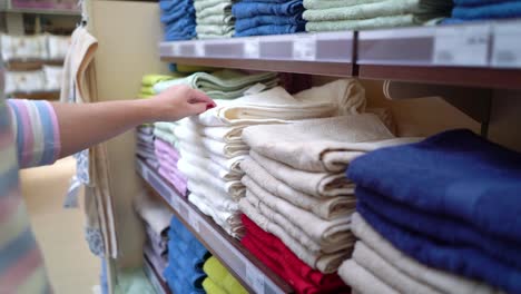 Mujer-caucásica-cerca-de-estantes-de-la-tienda-elegir-la-toalla-en-primer-plano-de-la-tienda