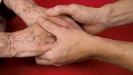 The-hands-of-a-man-stroke-the-hands-of-an-elderly-woman