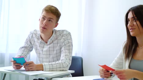 smiling-positive-male-student-answering-teacher-in-classroom