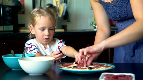 Kleines-Mädchen-legte-Oliven-auf-dem-Pizzaboden