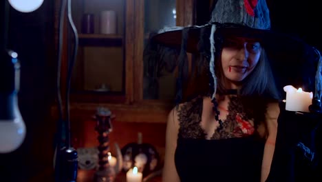 Halloween-witch-in-a-hat-takes-a-candle-in-her-hand-and-blows-it-out.