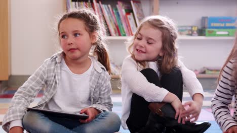 Two-elementary-schoolgirls-using-tablet-computer-in-class