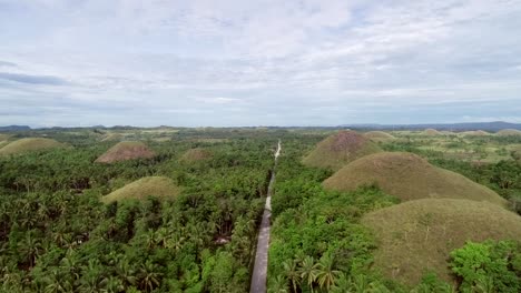 Camino-vista-aérea-cruzando-el-complejo-de-colinas-de-Chocolate,-Batuan,-Filipinas.