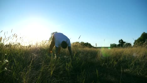 Junger-Mann-praktizierender-Yogaposition-auf-Matte-auf-der-Wiese.-Sportlicher-Typ-Stretch-Übung-im-Freien.-Sportler,-die-Ausbildung-am-Feld-an-einem-sonnigen-Tag.-Konzept-der-gesunden,-aktiven-Lebensstil.-Slow-Motion-hautnah