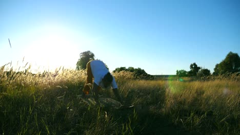 Young-man-practicing-yoga-position-on-mat-at-meadow.-Sporty-guy-doing-stretch-exercise-outdoor.-Athlete-training-at-field-on-a-sunny-day.-Concept-of-healthy-active-lifestyle.-Slow-motion-Close-up