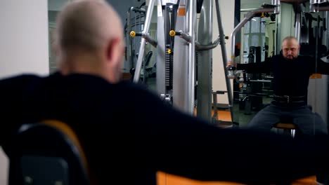 Strong-man-in-the-gym-shakes-hands.-Reflection-in-the-mirror-4K-Slow-Mo