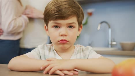 Child-sitting-at-a-table-and-parents-dancing-behind-him