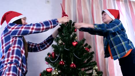 Mother-and-son-in-Christmas-hats-set-the-spire-on-top-of-the-Christmas-tree.