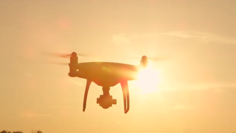 SLOW-MOTION-SILHOUETTE-Quadrocopter-Drohne-mit-rotierenden-Propeller-über-Sonne-fliegen