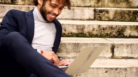 student-resting-on-steps-with-laptop-and-chatting