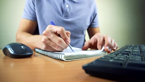 Close-up-of-hands-typing-on-computer-keyboard-and-mouse.-Writing-in-notebook