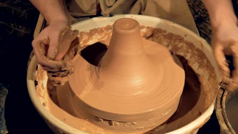 A-potter-uses-both-hands-to-throw-clay-into-a-tall-vase.