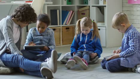 Frau-wenig-unterrichtet-Kinder-mit-digitalen-Tabletten-im-Kindergarten