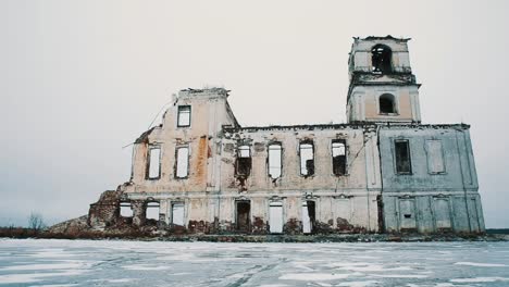 Abandoned-chapel-building-in-middle-of-frozen-lake-covered-in-snow