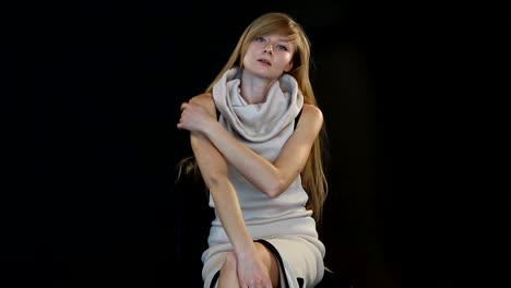 blonde-model-of-European-appearance-posing-in-front-of-camera-in-studio-on-black-background