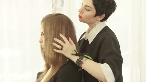 Estilista-hacer-peinado-para-pelo-largo-después-de-peluquería-en-estudio-de-belleza.-Cerca-de-haircutter-acabado-peinado-de-mujer-en-salón-de-peluquería