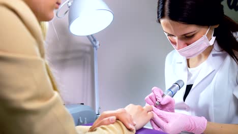 Beautician-careful-and-accurate-removing-cuticles-with-polish-machine