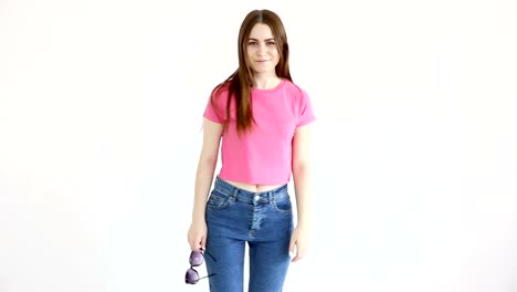 schöne-fröhliche-Mädchen-mit-Sonnenbrille,-Rosa-Top-und-Jeans-posiert-an-weißer-Wand