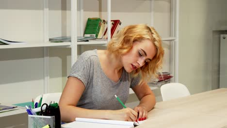 Gorgeous-young-woman-making-notes-while-studying