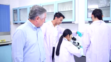 Scientists-working-in-lab-portrait.-Senior-chinese-male-scientist-working-in-lab-portrait-with-his-team-in-background.