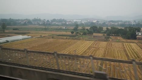 Vista-lateral-de-un-tren-de-pasajeros-de-la-zona-rural-de-China,-el-modo-de-movimiento-rápido.