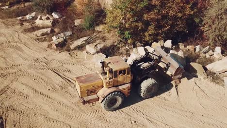 specially-equipped-machine-with-a-bucket-id-working-near-a-quarry-with-stones-on-the-background-of-sand.