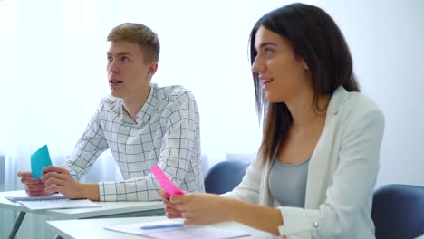 estudiantes-masculinos-y-femeninos-teniendo-tarjetas-de-color-y-hablar-de-asignación-en-el-aula-de-secundaria