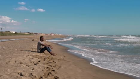 paz,-naturaleza,-relax.-Joven-negro-a-americano-sentado-en-el-océano-obersving-de-playa