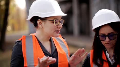 Engineer-communicates-and-demonstrates-the-construction-site-of-the-two-women-inspectors,-close-up